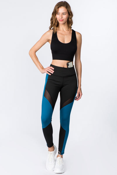 Women’s Black and Teal High Rise Colorblock Leggings with Mesh Panels and Side Pockets – breathable squat-proof workout leggings for gym, yoga, and running. Models hand is on her hip.